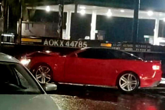 Vías del tren y vialidad pavimentada en una zona urbana durante la noche.