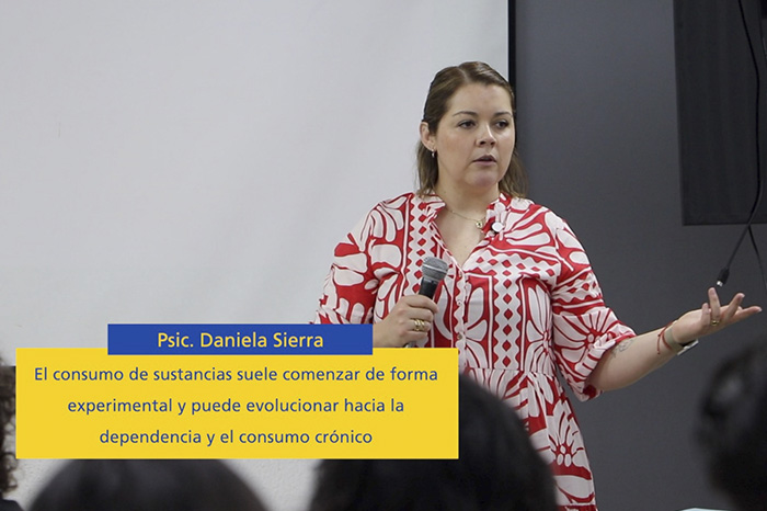 Especialista impartiendo una plática sobre salud mental ante un auditorio universitario.