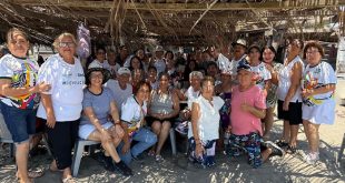 Grupo de adultos mayores conviviendo y sonriendo en un ambiente recreativo frente al mar.