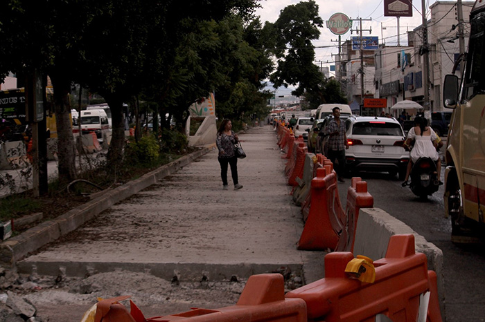 Automóviles transitando por una avenida urbana con infraestructura vial y semaforización.