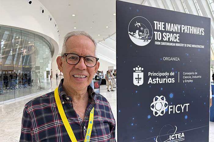 El experto en asteroides de la NASA, Humberto Campins, junto a un cartel del congreso 'The Many Pathways to Space' en Oviedo, España.