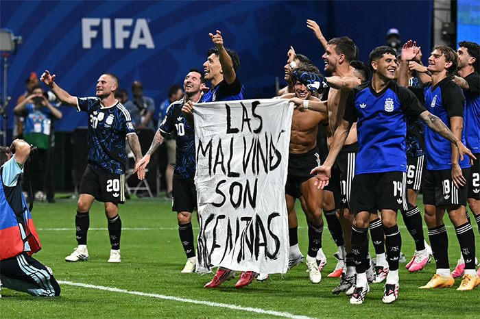 Jugadores de la selección de Argentina sostienen pancarta con la leyenda 'Las Malvinas son argentinas' en el terreno de juego.