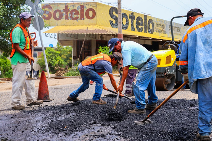 Maquinaria y personal realizando labores de bacheo y reencarpetamiento en una avenida urbana.