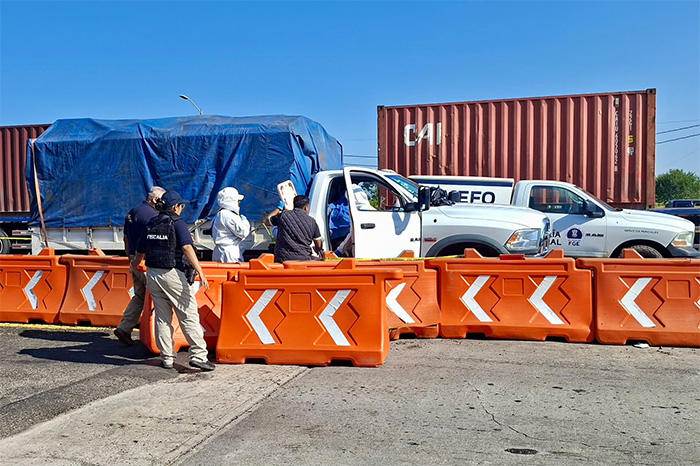 Peritos y elementos de seguridad trabajando junto a una camioneta blanca y contenedores tras el homicidio de un civil en la autopista de Occidente.