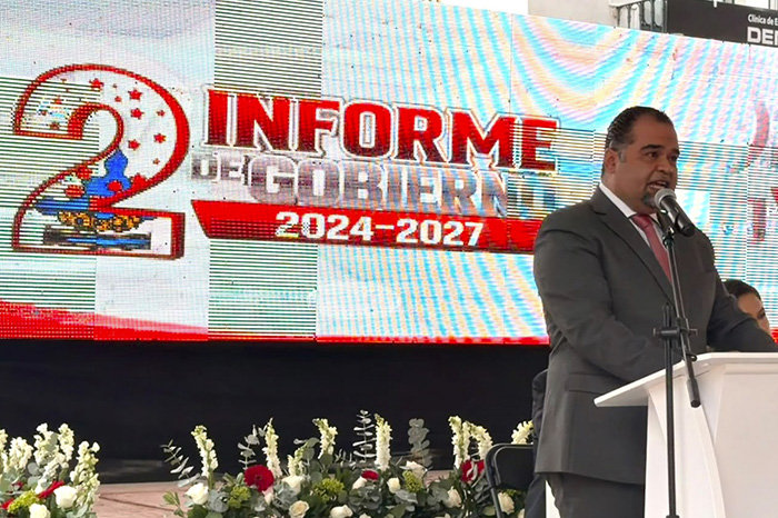 Presidente municipal dirigiéndose a los asistentes durante su informe anual de labores en un recinto público.