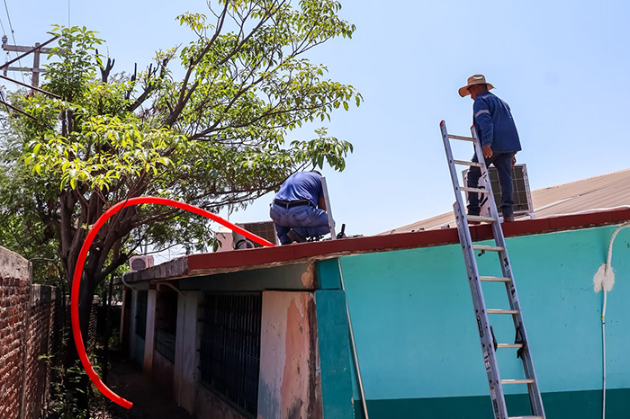 Personal municipal realizando labores de revisión y cambio de cableado eléctrico en una institución educativa.