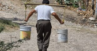 Persona cargando baldes de agua para abastecerse ante la sequía.