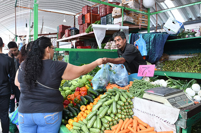Compradores adquiriendo productos de la canasta básica en un mercado local.