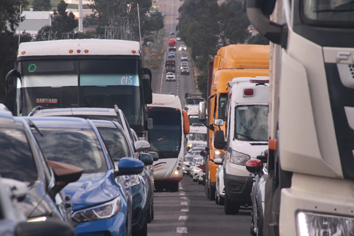Tránsito vehicular en una avenida urbana con señalización de seguridad vial.