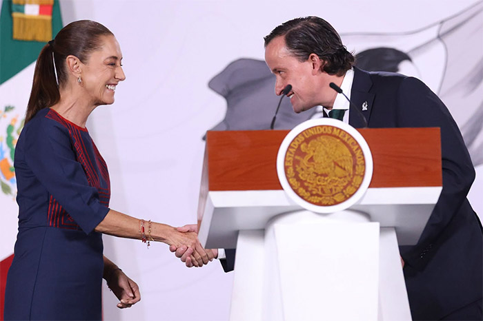 La presidenta Claudia Sheinbaum saluda a Mikel Arriola, directivo de la FMF, frente al atril presidencial.