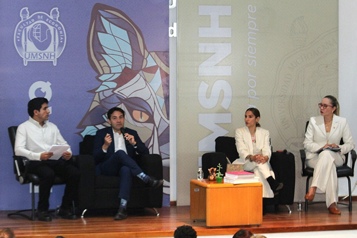 Panel de académicos y directivos durante la conferencia sobre migración en el auditorio de la Facultad de Economía.
