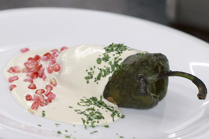 Platillo tradicional de chile en nogada bañado en crema de nuez de Castilla, granada y perejil.