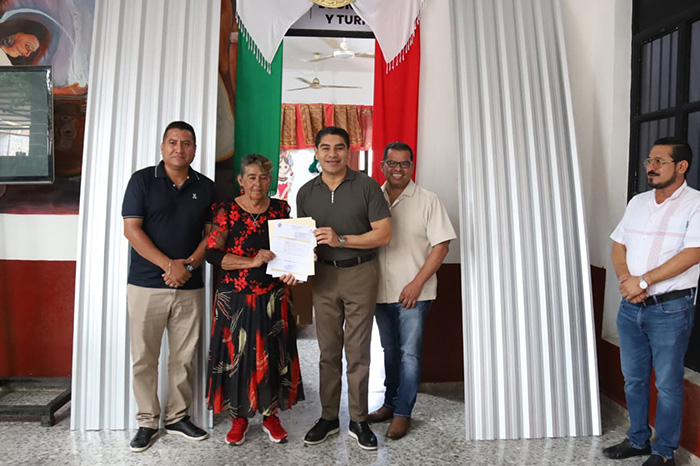 El presidente municipal de Huetamo entregando material de construcción a beneficiarios durante una jornada oficial.