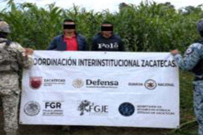 Dos personas detenidas y custodiadas por fuerzas de seguridad junto a una lona de coordinación interinstitucional en Zacatecas.
