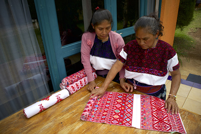Manos de artesanas indígenas tsotsiles elaborando bordados tradicionales en un telar de cintura en Chiapas.