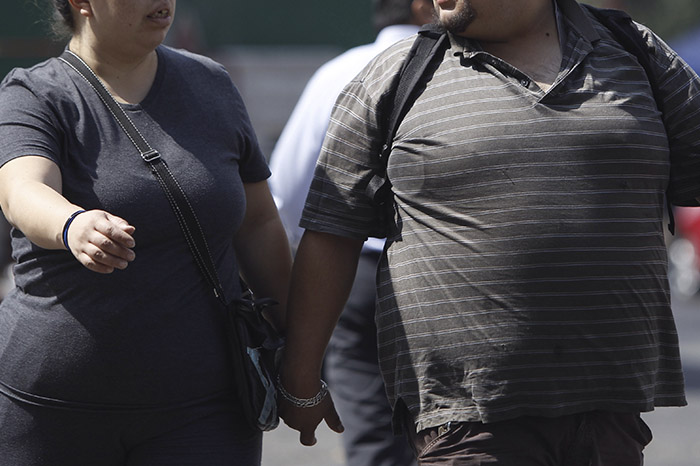Personas con obesidad y sobrepeso caminando en la calle.