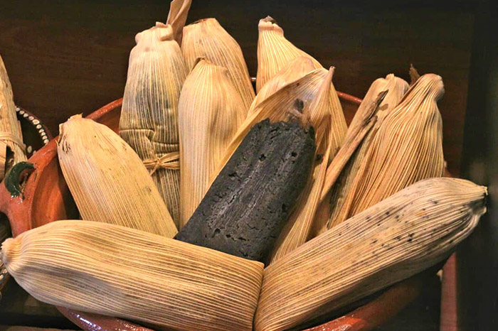 Platillos tradicionales de tamales y atole preparados por cocineras locales en Michoacán.