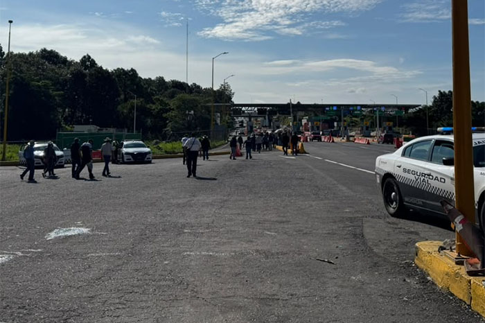 Comuneros indígenas bloqueando el paso vehicular en una caseta de cobro en la autopista Siglo XXI.