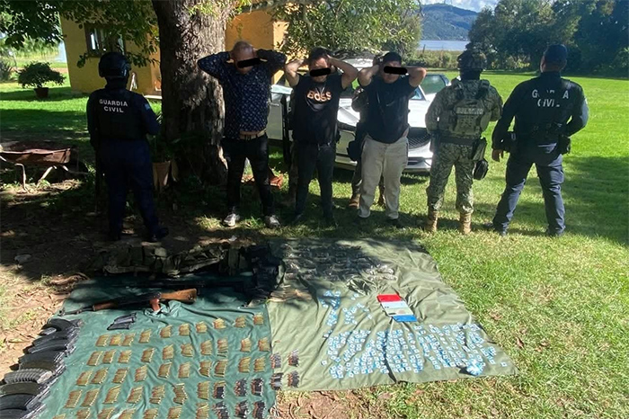 Fusiles, cargadores y dosis de sustancia ilícita sobre una mesa de evidencias junto a elementos de seguridad.