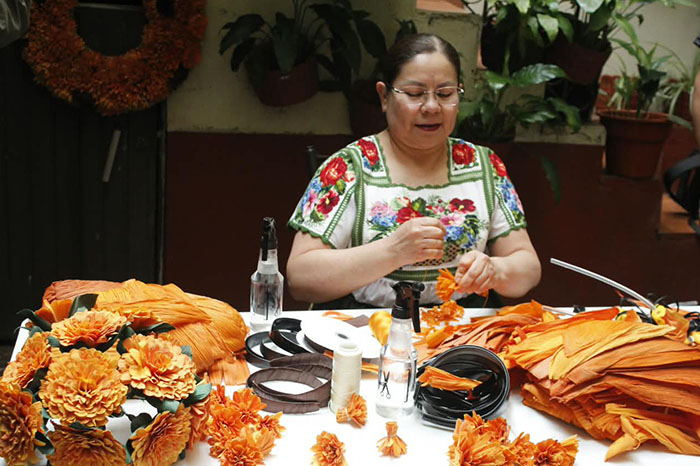 Manos artesanas elaborando figuras y flores decorativas con totomoxtle en un taller tradicional de Michoacán.