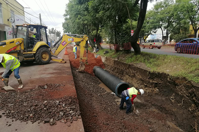 Maquinaria pesada y personal de construcción instalando tubos de drenaje pluvial sobre la avenida en Morelia.