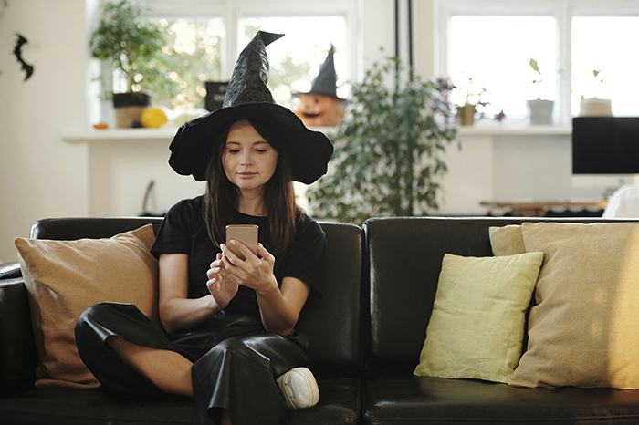 Personas utilizando teléfonos inteligentes para consultar disfraces y decoraciones de Halloween en redes sociales.