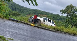 Agentes de tránsito y grúa remolcando una camioneta Jeep blanca volcada a un costado de la carretera.