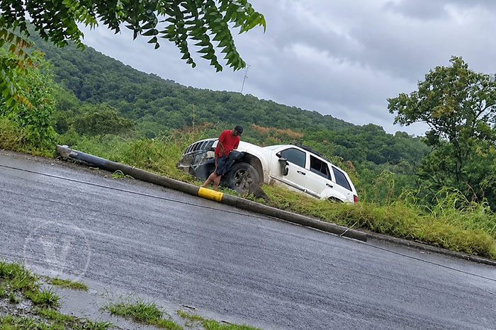 Agentes de tránsito y grúa remolcando una camioneta Jeep blanca volcada a un costado de la carretera.