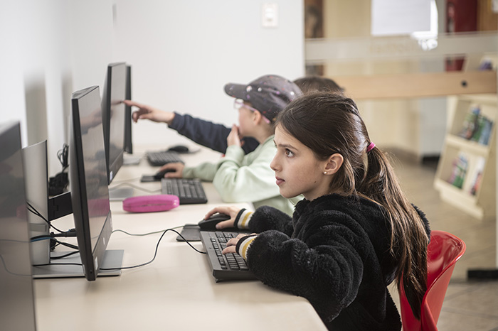 Docentes y alumnos utilizando herramientas tecnológicas y dispositivos digitales en un entorno escolar moderno.